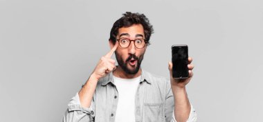 Genç, deli, sakallı adam. Düşünen ya da şüphe eden bir ifade. telefon ekranı kavramı
