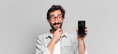Genç, deli, sakallı adam. Düşünen ya da şüphe eden bir ifade. telefon ekranı kavramı