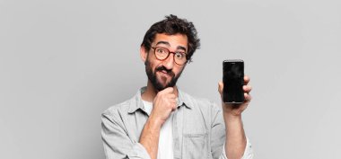 Genç, deli, sakallı adam. Düşünen ya da şüphe eden bir ifade. telefon ekranı kavramı