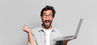 Genç, deli, sakallı adam. Zaferi kazanan gibi kutluyoruz. dizüstü bilgisayar