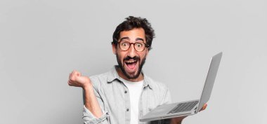 Genç, deli, sakallı adam. Zaferi kazanan gibi kutluyoruz. dizüstü bilgisayar