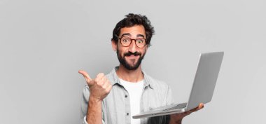 Genç, deli, sakallı adam. Mutlu ve şaşırmış bir ifade. dizüstü bilgisayar