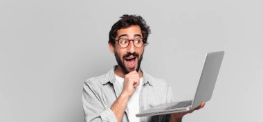 Genç, deli, sakallı adam. Düşünen ya da şüphe eden bir ifade. dizüstü bilgisayar