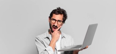 Genç, deli, sakallı adam. Düşünen ya da şüphe eden bir ifade. dizüstü bilgisayar