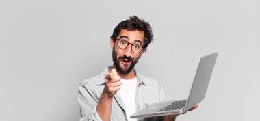 Genç, deli, sakallı adam. İşaret işareti. dizüstü bilgisayar