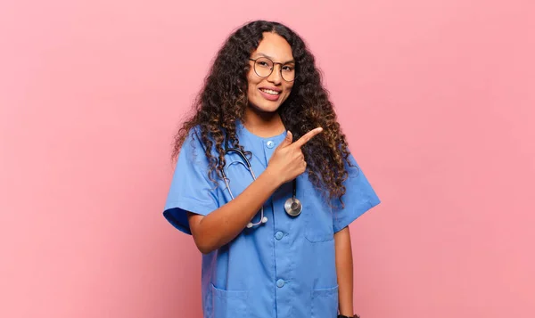 若いヒスパニック系の女性は興奮していると側に上方にスペースをコピーすることを指して驚いている 看護師の概念 — ストック写真