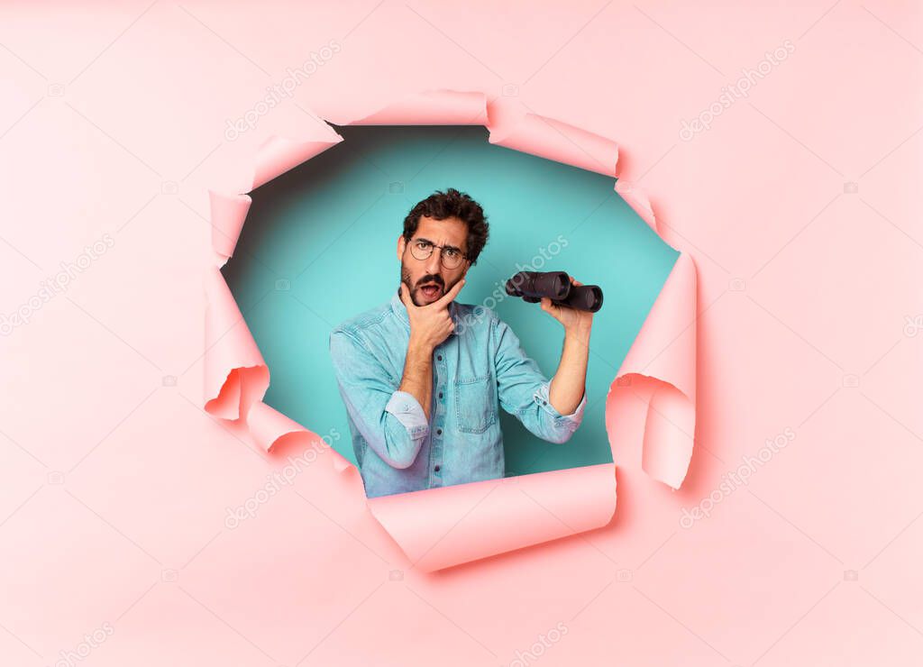 young crazy bearded man confused expression. binoculars concept