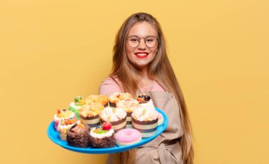 Genç ve güzel bir kadın. Mutlu ve şaşırmış ifade fırıncısı elinde keklerle