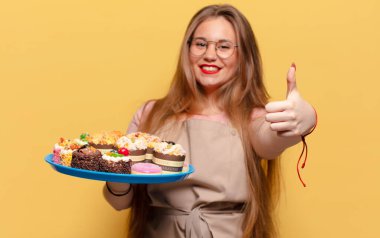 Genç ve güzel bir kadın. Mutlu ve şaşırmış ifade fırıncısı elinde keklerle