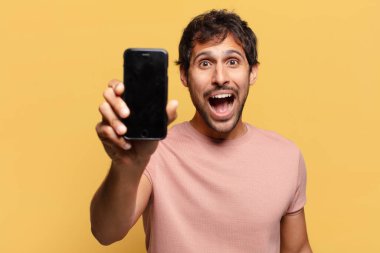 Genç, yakışıklı Hintli adam. şok ya da şaşırmış ifade akıllı telefon kavramı
