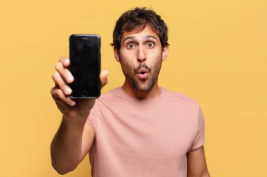 Genç, yakışıklı Hintli adam. şok ya da şaşırmış ifade akıllı telefon kavramı