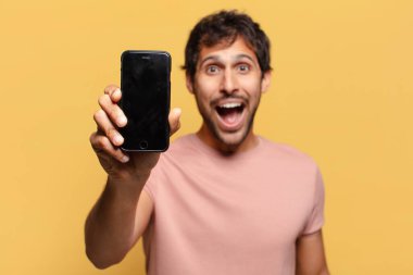 Genç, yakışıklı Hintli adam. şok ya da şaşırmış ifade akıllı telefon kavramı