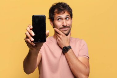 Genç, yakışıklı Hintli adamın kafası karışmış akıllı telefon konsepti