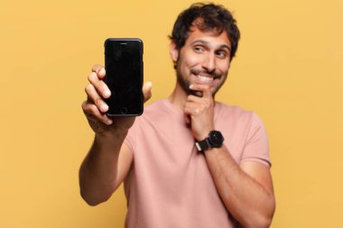 Genç, yakışıklı Hintli adam akıllı telefon konseptini düşünüyor.