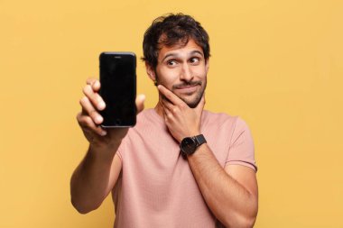 Genç, yakışıklı Hintli adamın kafası karışmış akıllı telefon konsepti