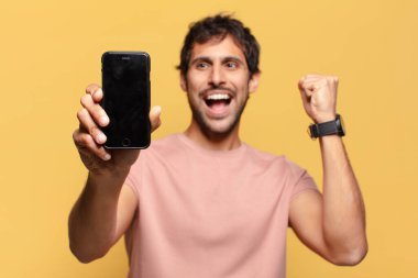 Genç ve yakışıklı Hintli adam kutlama ve gururlu ifade akıllı telefon kavramı