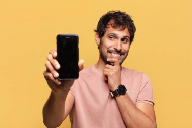 Genç, yakışıklı Hintli adam akıllı telefon konseptini düşünüyor.