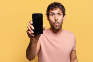 Genç, yakışıklı Hintli adam. şok ya da şaşırmış ifade akıllı telefon kavramı