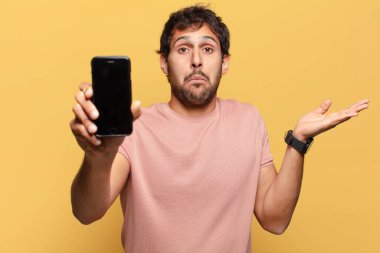 Genç, yakışıklı Hintli adamın kafası karışmış akıllı telefon konsepti