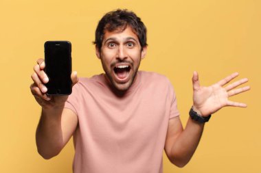 Genç, yakışıklı Hintli adam şaşırdı. Akıllı telefon kavramı.