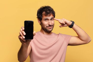 Genç, yakışıklı Hintli adam akıllı telefon konseptini düşünüyor.