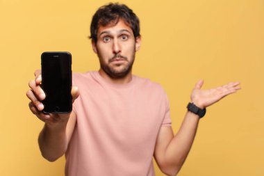 Genç, yakışıklı Hintli adamın kafası karışmış akıllı telefon konsepti