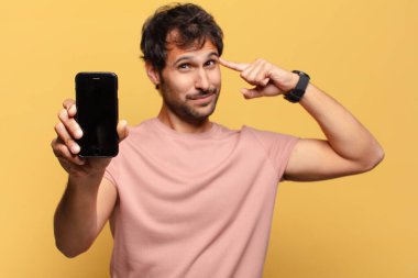 Genç, yakışıklı Hintli adam akıllı telefon konseptini düşünüyor.