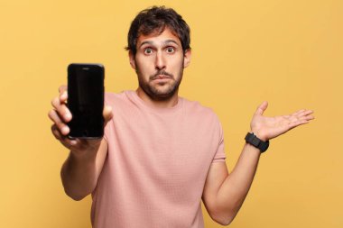 Genç, yakışıklı Hintli adamın kafası karışmış akıllı telefon konsepti