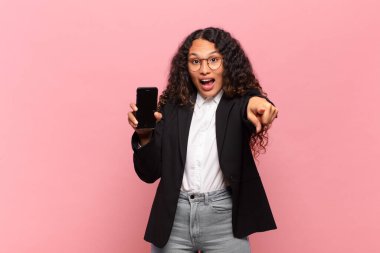 Genç, güzel, İspanyol bir kadın. Şaşırmış ya da şok olmuş. puanlı jest işi ve akıllı telefon kavramı