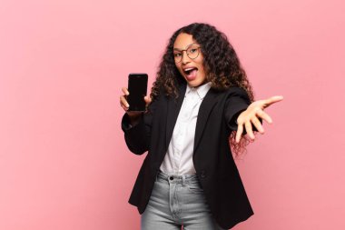 Genç, güzel, İspanyol bir kadın. Şok olmuş ya da şaşırmış ifade dünyası ve akıllı telefon kavramı