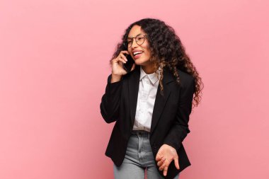 Genç, güzel, İspanyol bir kadın. Mutlu ve şaşırmış ifade işi ve akıllı telefon kavramı