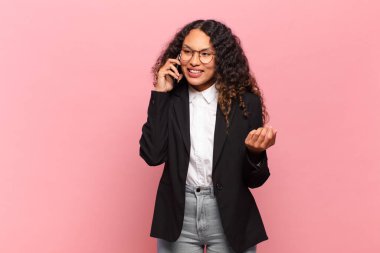 Genç, güzel, İspanyol bir kadın. Mutlu ve şaşırmış ifade işi ve akıllı telefon kavramı