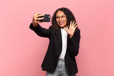 Genç, güzel, İspanyol bir kadın. Mutlu ve şaşırmış ifade işi ve akıllı telefon kavramı