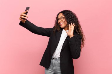 Genç, güzel, İspanyol bir kadın. Mutlu ve şaşırmış ifade işi ve akıllı telefon kavramı