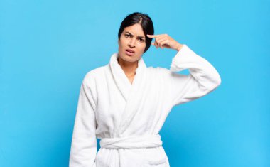 Genç İspanyol kadın şaşkın ve şaşkın hissediyor. Deli, deli ya da aklını kaçırmış olduğunu gösteriyor. Bornoz konsepti