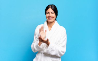 Genç İspanyol kadın mutlu ve başarılı hissediyor, gülümsüyor ve alkışlıyor, alkışlarla tebrik ediyor. Bornoz konsepti