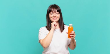 Mutlu, kendinden emin bir ifadeyle gülümsüyor, elleri çenesinde, merak ediyor ve yan tarafa bakıyor.