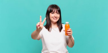 Gülümseyen ve mutlu görünen, kaygısız ve pozitif, tek elle zafer ya da barış işareti yapan