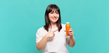 Neşeli bir şekilde gülümseyen, mutlu hisseden, kenarı ve yukarıyı gösteren, kopya uzayda nesneleri gösteren