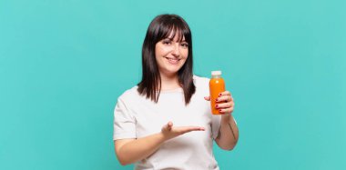 Neşeli bir şekilde gülümsüyor, mutlu hissediyor ve bir konsepti fotokopi uzayında avuç içiyle gösteriyor.