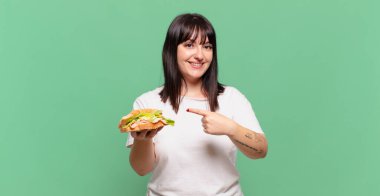 Neşeli bir şekilde gülümseyen, mutlu hisseden, kenarı ve yukarıyı gösteren, kopya uzayda nesneleri gösteren