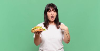 Şok olmuş ve şaşırmış bir halde, ağzı açık, kendini işaret eden.