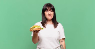 Şaşırmış ve kafası karışmış görünüyor, sinirsel bir hareketle dudağını ısırıyor, sorunun cevabını bilmiyor.