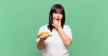 Ağzı ve gözleri açık ve elleri çenesinde, nahoş bir şekilde şokta, ne diyor ya da vay be