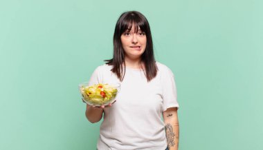 Şaşırmış ve kafası karışmış görünüyor, sinirsel bir hareketle dudağını ısırıyor, sorunun cevabını bilmiyor.