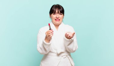 Bornoz giymiş genç bir kadın umutsuz ve hayal kırıklığına uğramış, stresli, mutsuz ve sinirli, bağırıyor ve çığlık atıyor.