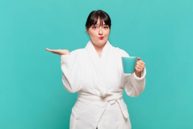 Bornoz giyen genç bir kadın şaşkın ve kafası karışık, şüpheci, tartılan ya da farklı seçenekleri komik bir ifadeyle seçen.