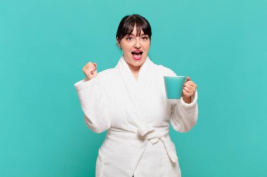 Bornoz giymiş genç bir kadın şok olmuş, heyecanlı ve mutlu, gülüyor ve başarıyı kutluyor,!