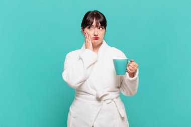 Bornoz giyen genç bir kadın yorgun, sıkıcı ve sıkıcı bir işin ardından sıkılmış, hayal kırıklığına uğramış ve uykulu hissediyor.