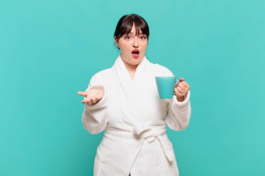 Bornoz giymiş genç bir kadın şok olmuş, şaşırmış, endişeli ve paniklemiş, stresli ve dehşete kapılmış görünüyor.